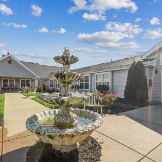 A serene courtyard featuring a decorative fountain under a bright blue sky.