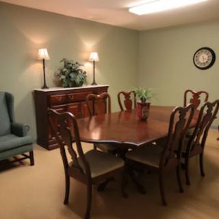 A neatly arranged dining room with a wooden table, chairs, and sideboard.