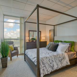 A modern bedroom featuring a stylish canopy bed, natural lighting, and tasteful decor.