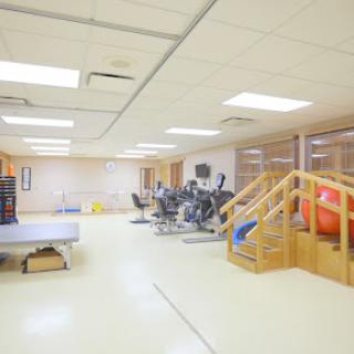 A spacious gym area equipped with various exercise machines, wooden stairs, and a stability ball for fitness and rehabilitation.