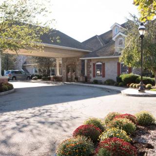 Entrance of a building with a driveway and landscaped surroundings.