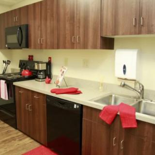 A modern kitchen with wooden cabinets and red accents.