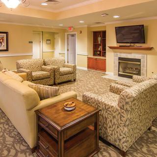 A cozy living room with comfortable seating arrangements, a fireplace, and a wall-mounted television.