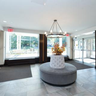 A modern lobby with stylish decor, featuring a central seating area and large windows.