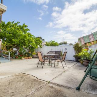 A sunny patio with outdoor furniture and lush greenery.