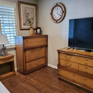 A cozy bedroom corner featuring wooden furniture, a mounted TV, and decorative elements.