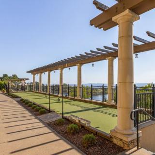 A scenic outdoor pathway with a pergola supported by stone columns, offering views of the surrounding landscape.