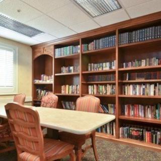 A cozy library room with wooden bookshelves, a table, and chairs.