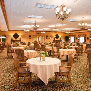 An elegant dining hall with neatly arranged tables and chandeliers overhead.
