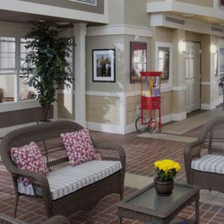 A cozy indoor seating area with wicker sofas, decorative cushions, a popcorn machine, and potted flowers.