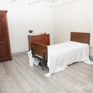 A minimalist bedroom with a wooden bed, dresser, and wardrobe.