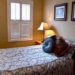 A cozy bedroom with a neatly made bed, decorative pillows, and wall art.