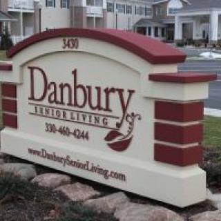 A sign for Danbury Senior Living, featuring contact details and a web address.
