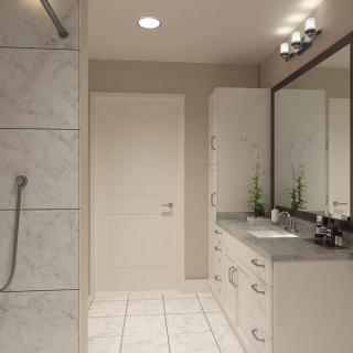 A modern bathroom featuring a large mirror, sleek sink and cabinet, tiled flooring, and a spacious shower area.
