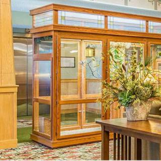 A classic wooden elevator with decorative plants in a traditionally styled interior.