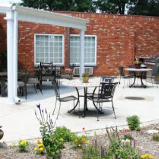 A serene outdoor patio area with tables, chairs, and vibrant flowers.