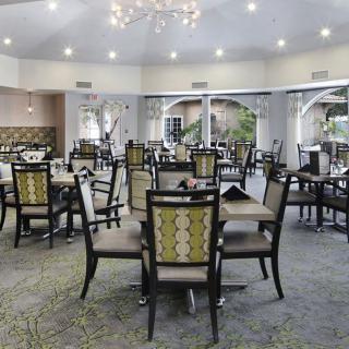 A spacious and elegantly designed dining area with multiple tables and chairs, featuring a chandelier and modern decor.