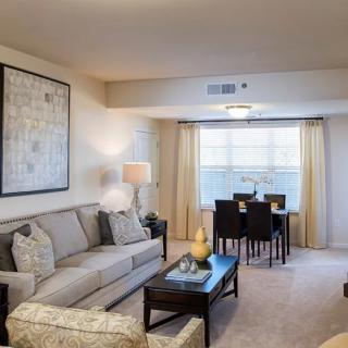 A cozy living room with a sofa, coffee table, and a dining area by the window.