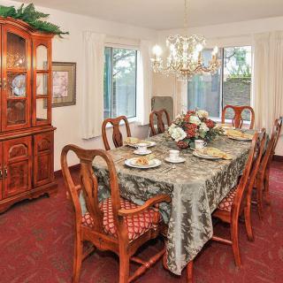 A cozy dining room with a large table set for a meal, featuring elegant wooden chairs and a chandelier overhead.
