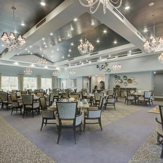 A spacious and elegantly decorated dining area with chandeliers and stylish furniture.