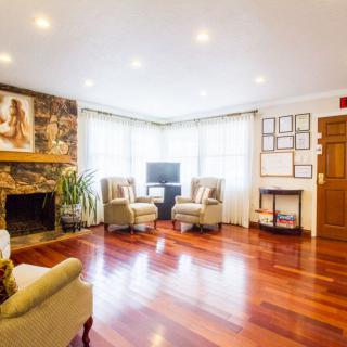 A cozy living room with hardwood flooring, featuring a fireplace and comfortable seating.