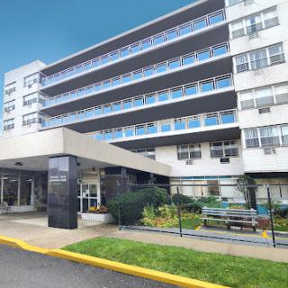 A modern residential building featuring multiple floors and landscaped surroundings.