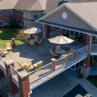 Aerial view of a building with a spacious balcony featuring outdoor seating and umbrellas.