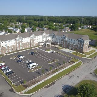 Aerial view of a residential building with a parking lot in a suburban area.