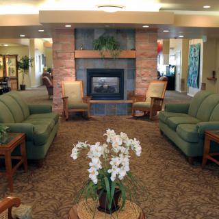 A cozy living room with sofas and a fireplace, adorned with an orchid centerpiece.
