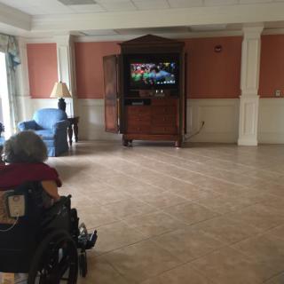 A person in a wheelchair watching a television in an empty room.