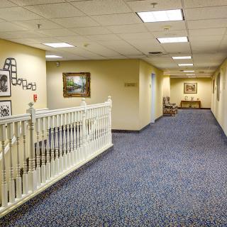 A well-lit hallway with carpeted floors and framed artwork on the walls.