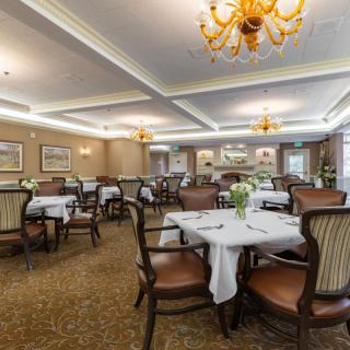 An elegant dining room with neatly arranged tables and chairs, adorned with chandeliers.