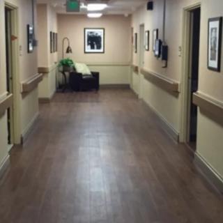 A quiet hospital hallway with artwork on the walls and a seating area at the end.
