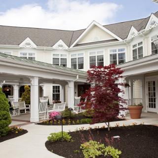 A picturesque courtyard featuring a residential building with charming architectural details and landscaped gardens.
