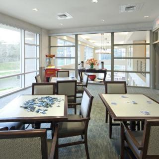 A modern dining area with tables and chairs, featuring large windows for natural light.