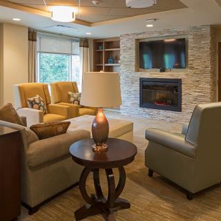 A cozy and modern living room with comfortable seating around a stone fireplace.