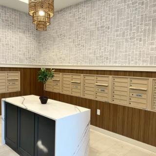 A modern mail room with a row of mailboxes, a central counter, and elegant decor.