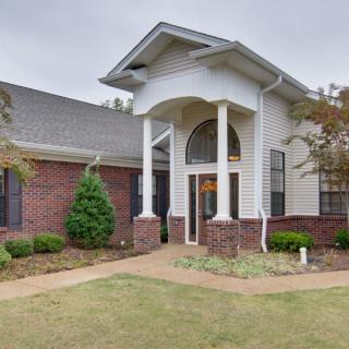 A brick and white residential house with columns at the entrance and a well-maintained lawn.