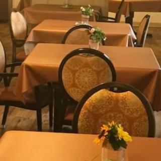 A cozy restaurant setting with tables covered in brown tablecloths and small floral arrangements.