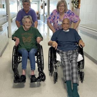 A heartwarming moment in a hospital as elderly individuals enjoy some time with their caregivers.