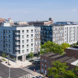 A modern residential apartment building in an urban setting, surrounded by streets and greenery.
