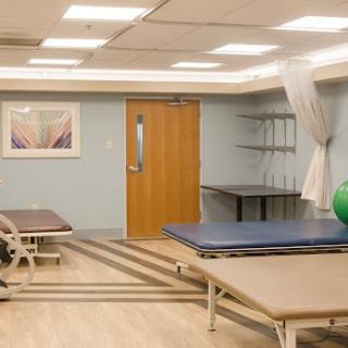 A spacious and well-lit physical therapy room, equipped with exercise mats and a fitness ball.