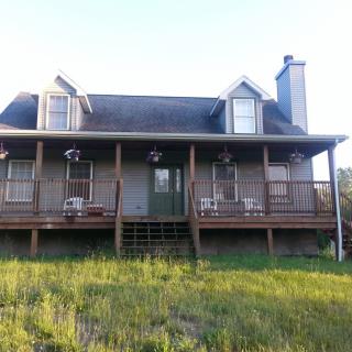 A country-style house with a spacious porch and grassy front yard.