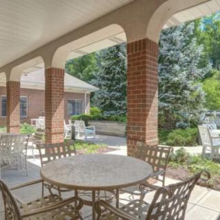 A covered patio with tables and chairs overlooking a garden.