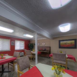 A cozy dining room with tables set and decorated with flowers.