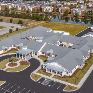 An aerial view of a large building complex with a parking lot in a suburban area.