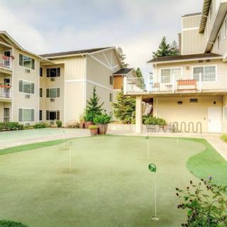 An apartment complex featuring a well-maintained putting green surrounded by landscaped greenery.