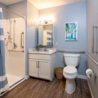 A modern bathroom with a glass shower, toilet, and vanity sink under soft lighting.