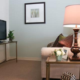 A cozy living room with a sofa, decorative pillows, a lamp on a side table, and a television set against the wall.