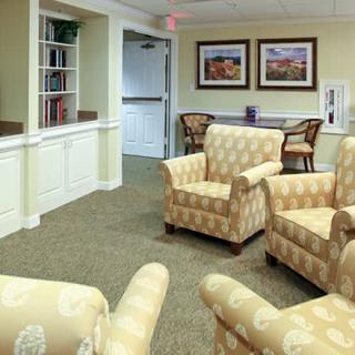 A cozy living room with patterned armchairs and framed paintings on the wall.